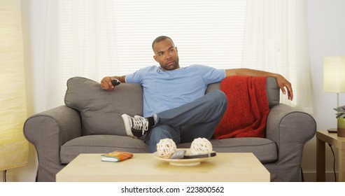 Black Man Sitting On Couch Watching Tv