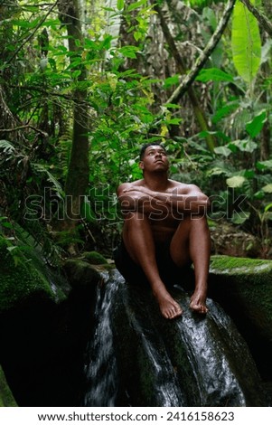 black man sitting on a rock in the middle of nature near a waterfall.|  Homem negro sentado em uma pedra no meio da natureza proximo de uma cachoeira que fica na chapada diamantina - Brasil