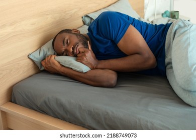 Black Man Sleeping Embracing Pillow Lying In Bed In Modern Bedroom Indoor In The Morning. Guy Napping Peacefully Resting At Home. Healthy Sleep Concept