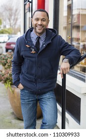 Black Man Standing In The Street Leaning Of A Railing And Looking Straight Into The Camera.