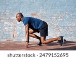 Black man, start position and outdoor for running, workout and marathon training in city. Fitness, male athlete and ready for race or challenge in street or urban area for wellness, health and cardio