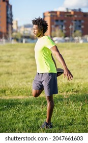 Black man stretching his quadriceps after running outdoors.