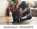 Black man, stretching and legs with mat for workout, exercise or fitness on floor at home. Active, young African or male person in warm up, preparation or getting ready for yoga, pilates or training