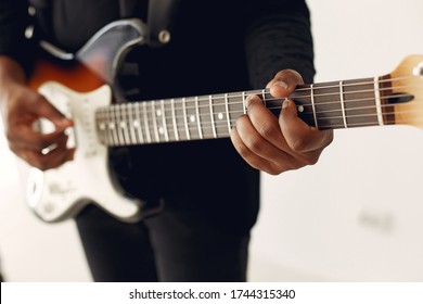 Black man in a studio. Guy in a black suit. Musician with a guitar. - Powered by Shutterstock