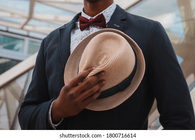 Black Man In Suit And Bowtie Holding Hat On Chest