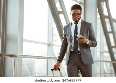 Black man with a suitcase is chatting on his phone outside an airport terminal. The scene is professional and busy, capturing the essence of corporate travel. - Powered by Shutterstock