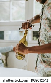 Black Man Uncorking A White Wine Bottle