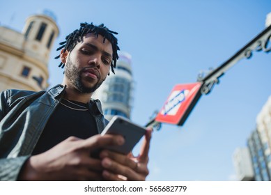 Black Man Using Phone In Front Of A Subway Station. Horizontal Shoot Outdoors