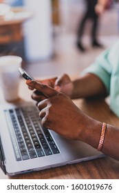 Black Man Using Phone And Laptop At Coffee Shop