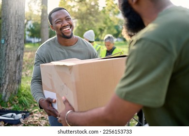 Black man, volunteering and giving box in park of donation, community service or social responsibility. Happy guy, NGO worker and helping with package outdoor for charity, support or society outreach - Powered by Shutterstock