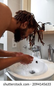 Black Man Washing His Face With Water In Wash Basin In Bathroom At Home. Concept Of Domestic Lifestyle. Idea Of Face Care. Cropped Image Of Young Bearded Dark Haired Guy. Mrning Time