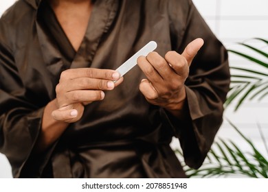 Black Man Wearing Bathrobe Doing Manicure With Nail File In Bathroom