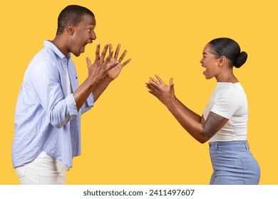 Black man and woman engage in playful gestures with exaggerated surprised expressions, creating humorous and lively scene on vivid yellow background