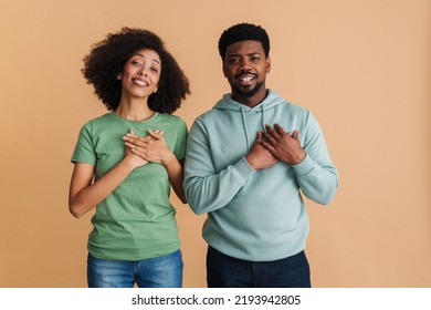 Black man and woman expressing dignity and keeping their hands at heart isolated over beige background - Shutterstock ID 2193942805