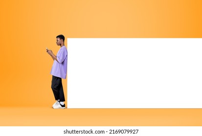 Black Man Working With Phone, Texting On Yellow Background. Concept Of Online Communication And Mobile App. Mock Up Copy Space Whiteboard