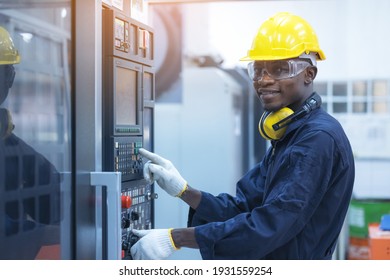 Black man working at programmable machine in factory industries 