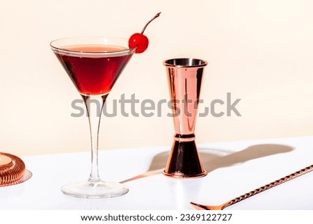 Black Manhattan alcoholic cocktail with whiskey and red vermouth garnished with maraschino cherry in martini glass. Beige background, hard light