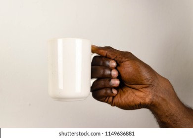 Black Man's Hand Holding White Cup Of Coffee Or Tea On White Background. African American Hands Holding A Cup Of Coffee Isolated On White Background