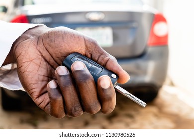 Black man's hand presses on the remote control car alarm systems. A African American man's hand holding car keys and a remote control for keyless entry.