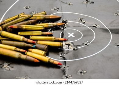 black man-target shooting paper which has pile of bullets or ammunitions above, soft and selective focus on x letter inside the circle of man-target shooting paper.