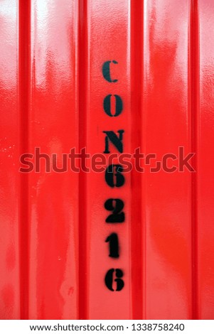 Black markings sprayed on the wall of a red shipping container, close detail view.