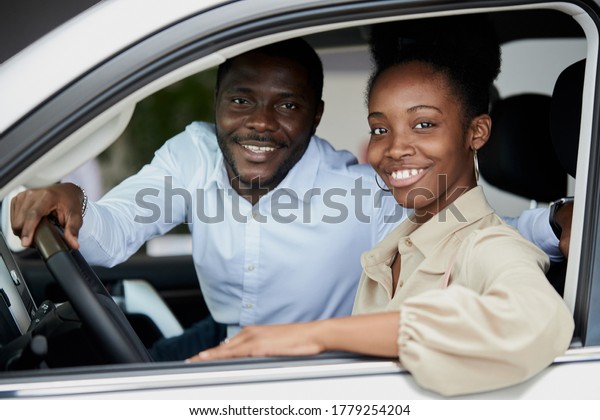 black married family examining car from\
inside, they are checking convenience and look characteristics of\
automobile in dealership, want to buy\
it