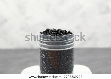 Black masterbatch in plastic jar. Polyethene or Polythene. PE granules. Granulated plastic polymer. Carbon black dyed polyethylene pellets.