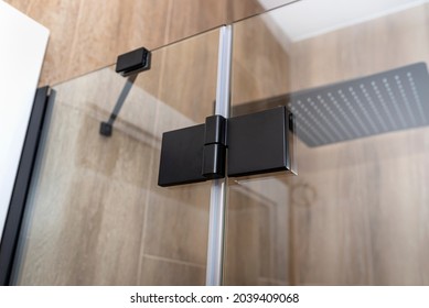 Black matt hinge connecting the wings of the shower enclosure flush with the glass, view from outside.