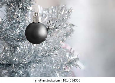 Black matte metallic ornament hanging on a silver artificial Christmas tree with copy space - Powered by Shutterstock