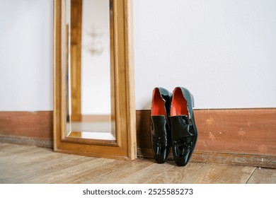 Black men patent leather Christian Louboutin shoes stand against the wall near the floor mirror