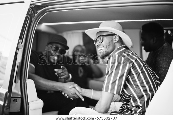 Black men wearing cool traditional clothes\
in the minivan. Black and white\
photo.
