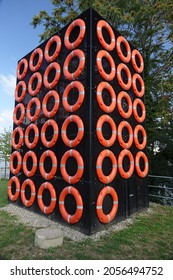 Black Mesh Wire Cube Covered With Shiny Orange Life Buoys At The Rhine Shore, Huningue, Haut Rhin, Alsace, Grand Est, France