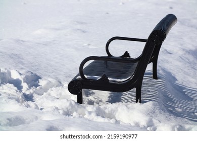 A Black Metal Bench In A Pile Of Snow