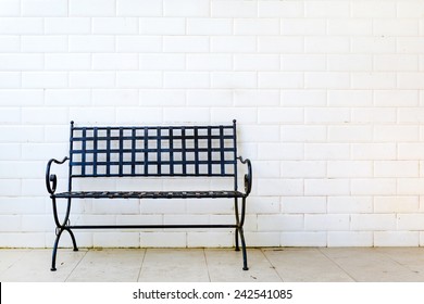 Black Metal Bench With White Brick Wall