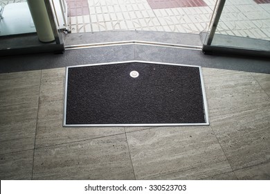 Black with metal frame mat on the gray stone floor near metal glass sliding door