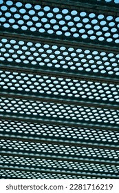 Black metal grate drain vent and holes in geometric pattern for background texture image and background sky  In industrial area and light pattern   horizonal beams in city 