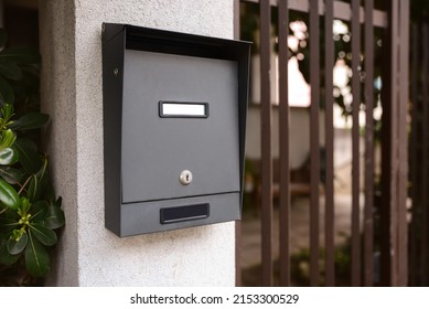 Black metal mailbox outdoors near entrance on spring day