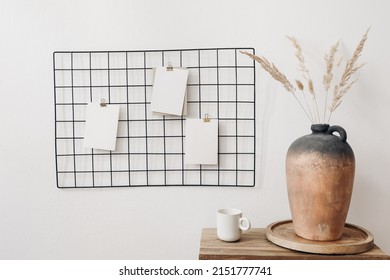 Black Metal Mesh Noticeboard, Bulletin Board With Blank Memo Cards Mockups. Elegant Home Office Interior Concept. Vase With Dry Lagurus Grass And Cup Of Coffe On Wooden Table. White Wall Background.