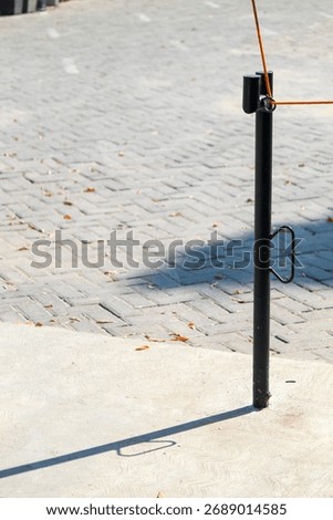 Black metal pole casting shadow on pavement