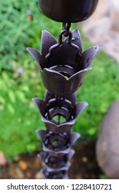 Black Metal Rain Chains In A Garden On Blurred Background