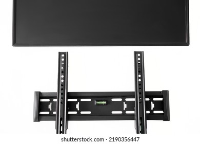 Black Metal TV Wall Mount Bracket And Flat Black Monitor Screen Isolated On White Background. Mounting A Modern TV Or Computer Monitor On The Wall. Bubble Level. Close-up