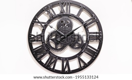 Black metal Wall Clock. Shadows over the clock face. Gears in the middle of the clock. Old antique metal. Watch show how the time. Rustic black watch on white background. Ten after ten