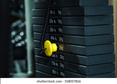 Black metallic or iron heavy plates stacked for sport, exercise, weight machine with kilogram and pound numbers in fitness gym on blurred grey background
