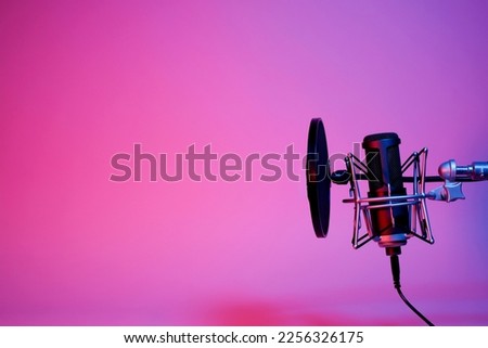 black microphone on pink and purple neon background with copy space. 