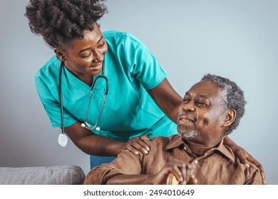 A black mid-adult female nurse in teal scrubs provides attentive care to an elderly black man, ensuring his comfort during a home health visit. - Powered by Shutterstock