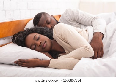 Black Millennial Couple Sleeping Together In Comfortable Bed At Home, Man Embracing His Wife From Back.