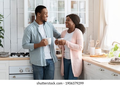 Black Millennial Couple Spending Time In Kitchen Together, Drinking Coffee And Chatting, Happy Young African American Man And Woman Enjoying Hot Drink In Cozy Interior And Smiling, Free Space