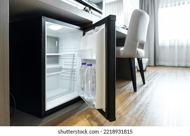 Minifrigorífico frigorífico pequeño negro bajo el cuadro mostrador de madera en el dormitorio del complejo del hotel