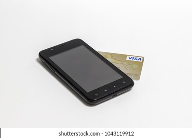 Black Mobile Phone With Gold Plastic Credit Card Visa Isolated On A White Background