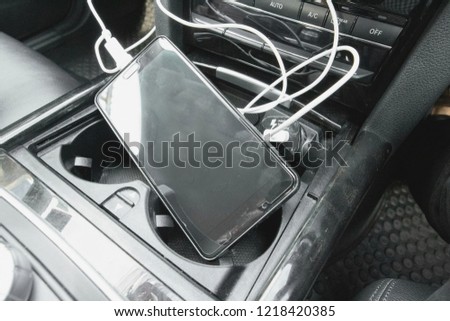 Black mobile phone still charge power battery on the black console of the modern luxury super car.